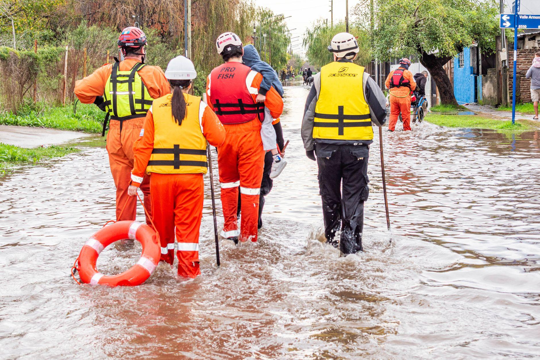 A rescue crew in life jackets wading through a flooded street